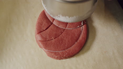 A-person-hand-pressing-down-on-a-red-cookie-dough-making-designs,-close-up-static