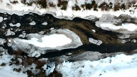 Small-Frozen-River-Bank-in-snowy-landscape-during-wintertime