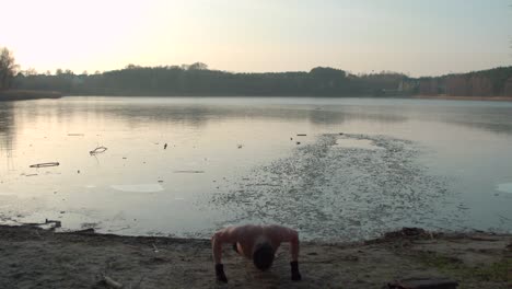 Young-man-doing-pushups-near-a-frozen-lake-bed