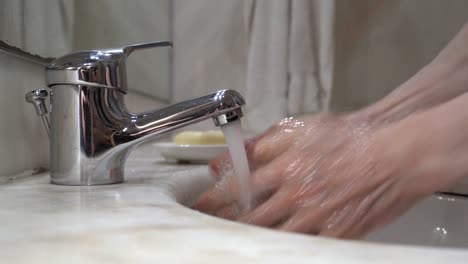 old-man's-hand's-are-washed-on-tap-water-with-soap,-then-rinsed-and-wiped-on-a-white-cloth-towel---side-view-static-close-up-shot-4k