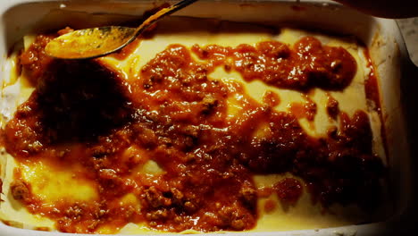 Während-Der-Zubereitung-Einer-Lasagne-Die-Bolognese-Sauce-Mit-Einem-Löffel-Verteilen