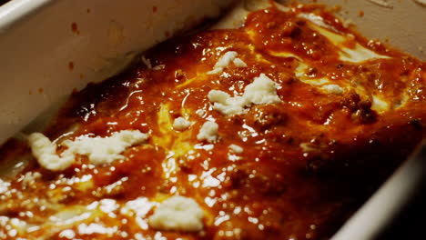 Sprinkling-mozzarella-cheese-above-of-bolognese-sauce,-making-lasagna-recipe