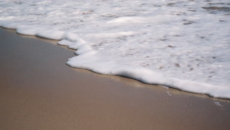 Handheld-closeup-shot-of-waves-crashing-onto-an-empty-beach