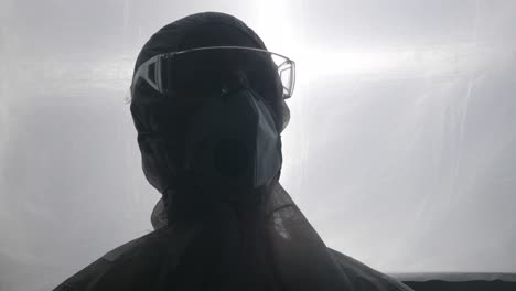 Lab-worker-in-medical-protective-suit,-face-mask-and-goggles-nervously-looks-around-laboratory