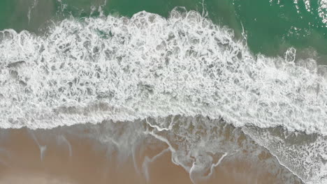 Aerial-top-down-shot-of-Splashing-ocean-Waves-And-Beach-At-Gold-Coast
