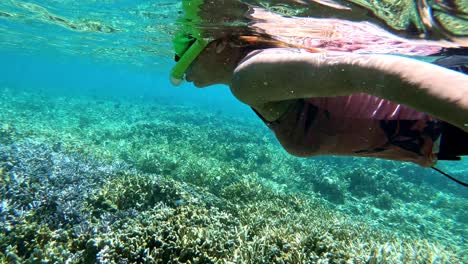 Asian-woman-enjoying-snorkeling-above-the-stony-corals-on-the-turquoise-sea-water-of-Cebu,-Philippines