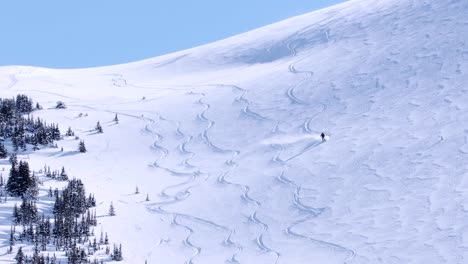 Backcountry-skier-carves-turns-on-virgin-snow-slope-in-mountain-winter