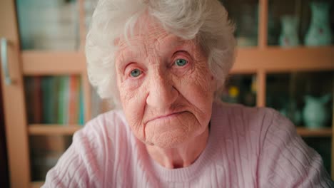 Close-up-face-of-a-sad-old-woman-with-deep-wrinkles-winking-her-eyes
