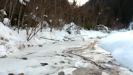 Small-Frozen-River-Bank-in-snowy-landscape-during-wintertime