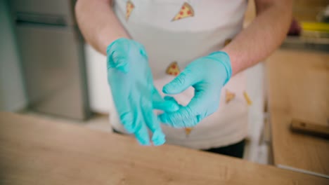 Man-wearing-gloves-at-the-kitchen-in-a-close-up-view