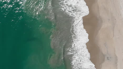 Slow-aerial-drone-footage-above-tropical-ocean-shore-with-breaking-waves
