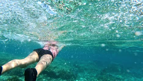 Mujer-Nadando-A-Lo-Largo-De-La-Parte-Poco-Profunda-Del-Mar,-Por-Encima-De-Los-Corales-Rocosos