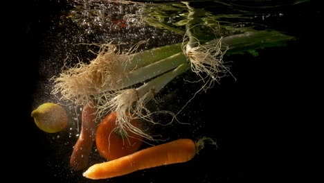 Green-onions,-tomato,-carrots-and-lemon-falling-together-in-the-clear-and-dark-water