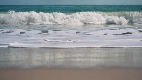 Slow-motion-low-angle-shot-showing-breaking-waves-on-sea-shore-during-beautiful-day