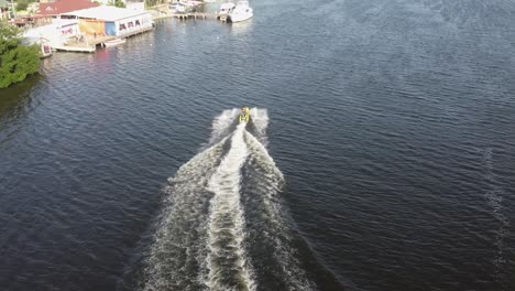 Bird's-eye-view-Drone-flight-behind-a-jetsky-traveling-over-the-water