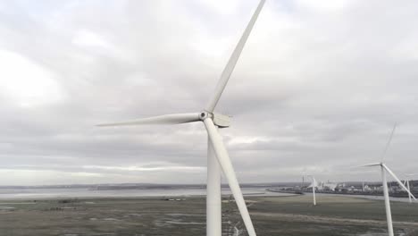 Sustainable-electrical-wind-turbines-spinning-on-England-farmland-skyline-orbit-left-aerial-view