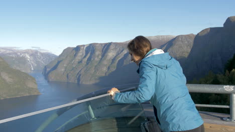 Una-Mujer-Disfruta-De-Una-Vista-Impresionante-De-Las-Montañas-Y-Un-Fiordo-Desde-La-Plataforma-De-Observación-Stegastein-En-Noruega,-Cámara-Lenta