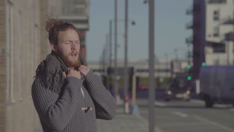 Man-wearing-scarf-standing-on-the-street-breathing-deeply