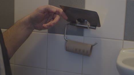 Hand-grabbing-Last-sheet-of-toiletpaper-on-roll-in-bathroom
