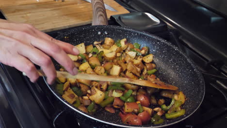Cooking-mixed-vegetables-and-fried-potatoes-in-frying-pan-at-home,-slow-motion