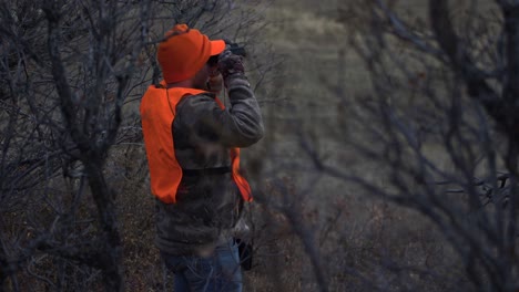 Hunter-Stands-and-Looks-through-Binoculars.-Handheld-4K