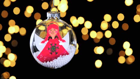 Einzelne-Klare-Weihnachtskugel-Ornament-Mit-Cartoon-Roten-Haarengel-Und-Schnee-Im-Inneren-Unscharf-Lichter-Flackern-Im-Hintergrund,-Nahaufnahme