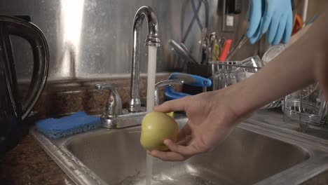 Limpiando-La-Pequeña-Manzana-Dorada-En-El-Fregadero-De-La-Cocina