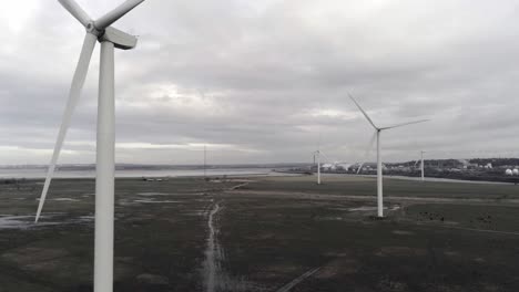 Nachhaltige-Elektrische-Windkraftanlagen,-Die-Sich-Auf-Englischem-Ackerland-Drehen,-Ziehen-Sich-In-Die-Nähe-Der-Rotorblätter-Zurück