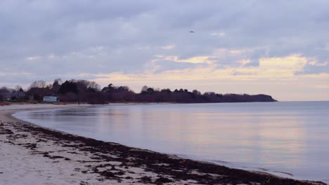 Statische-Ansicht-Der-Ostsee,-Die-Einen-Leeren,-Gebogenen-Strand-Bei-Lapmezciems-In-Lettland-Trifft,-Mit-Sonnenuntergang,-Der-Sich-Auf-Dem-Wasser-Spiegelt