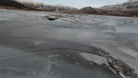 Volando-Sobre-El-Lago-Congelado-Por-Las-Montañas-Nevadas-De-Islandia---Antena