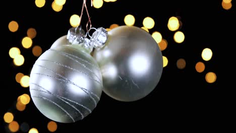 Drei-Silberne-Weihnachtskugeln-Mit-Unscharfen-Lichtern,-Die-Im-Hintergrund-Flackern,-Nahaufnahme