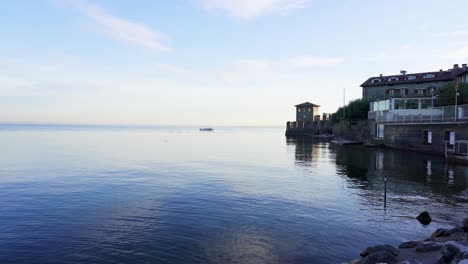 Tranquil-scene-on-the-shores-of-Lake-Garda-with-tourists-enjoying-the-beach-and-fortification-of-the-water-castle-in-Sirmione