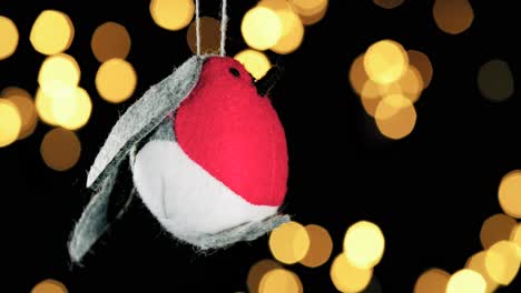 Single-Häkeln-Red-Robin-Bird-Christmas-Ornament-Mit-Unscharfen-Lichtern,-Die-Im-Hintergrund-Flackern,-Nahaufnahme