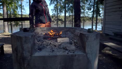 A-female-hiker-grilling-a-hot-dog-on-a-small-campfire-by-a-campsite-in-the-forest