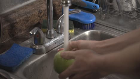 Reinigung-Von-Grünem-Apfel-Mit-Einer-Hand-Auf-Der-Küchenspüle