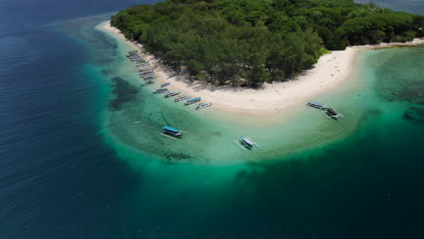 Aerial-orbital-shot-over-a-tropical-island-in-the-blue-ocean,-tourists-visiting-in-Asia-by-traditional-boats
