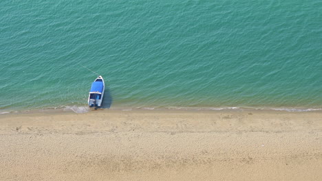 Boat-near-the-sandy-beach-from-top-view