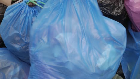A-full-bag-of-rubbish-being-tossed-on-top-of-a-large-pile-of-garbage-bags