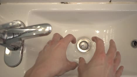 Zwei-Große-Hände,-Die-Das-Wasser-In-Das-Weiße-Waschbecken-Tropfen-Ließen
