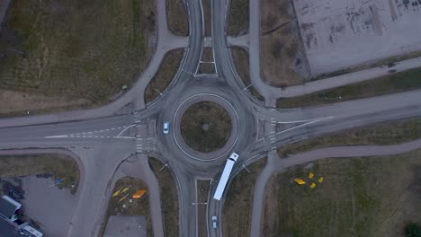 Drone-footage-showing-cars-and-a-truck-driving-in-and-out-of-a-roundabout-on-a-cloudy-day-in-march-2020