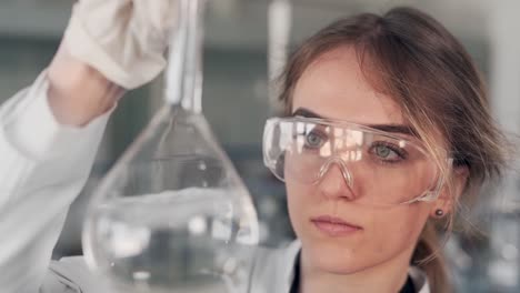 closeup-portrait-of-female-scientist-examining-liquid-in-test-tube-with-magnifier