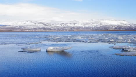 The-cold,-icy-river-of-Iceland-by-white-mountains---wide-shot