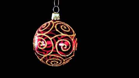 single-red-clear-Christmas-ball-ornament-with-golden-glitter-stripes-and-black-background,-close-up