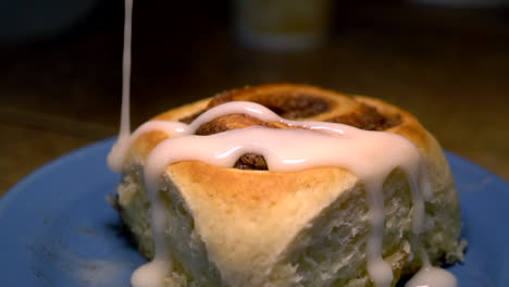 A-Person-Putting-An-Icing-In-The-Delicious-Cinnamon-Rolls-On-The-Plate---Closeup-Shot