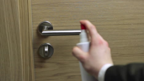 Spraying-a-metallic-door-handle-with-a-disinfectant-cleanser-to-sterilise-it-to-avoid-spreading-germs