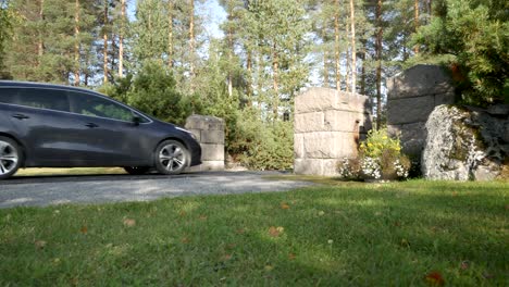 A-car-driving-through-the-entrance-to-a-cemetery-in-Sweden-on-a-sunny-day