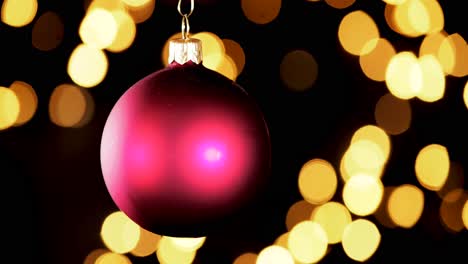 Single-Red-Christmas-Ball-Ornament-Mit-Unscharfen-Lichtern,-Die-Im-Hintergrund-Flackern,-Nahaufnahme