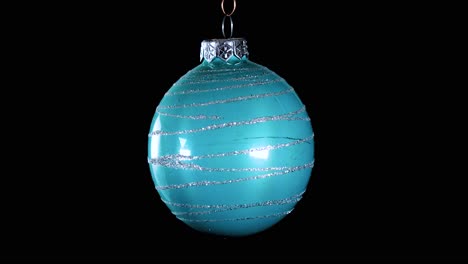 single-blue-turquoise-Christmas-ball-ornament-with-glitter-stripes-and-black-background,-close-up