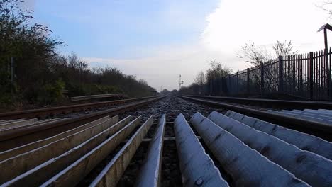 Low-angle-view-looking-down-empty-railway-tracks-under-blue-cloudy-sky