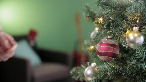 Mann-Schmückt-Den-Weihnachtsbaum-Mit-Einer-Roten-Weihnachtskugel